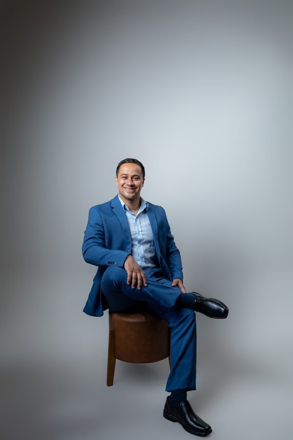 Eliel Miranda sentado, em um retrato de terno azul